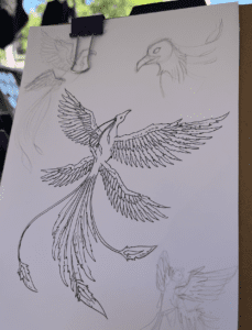 Photo of a sketch of a four-winged phoenix pinned up on a board.